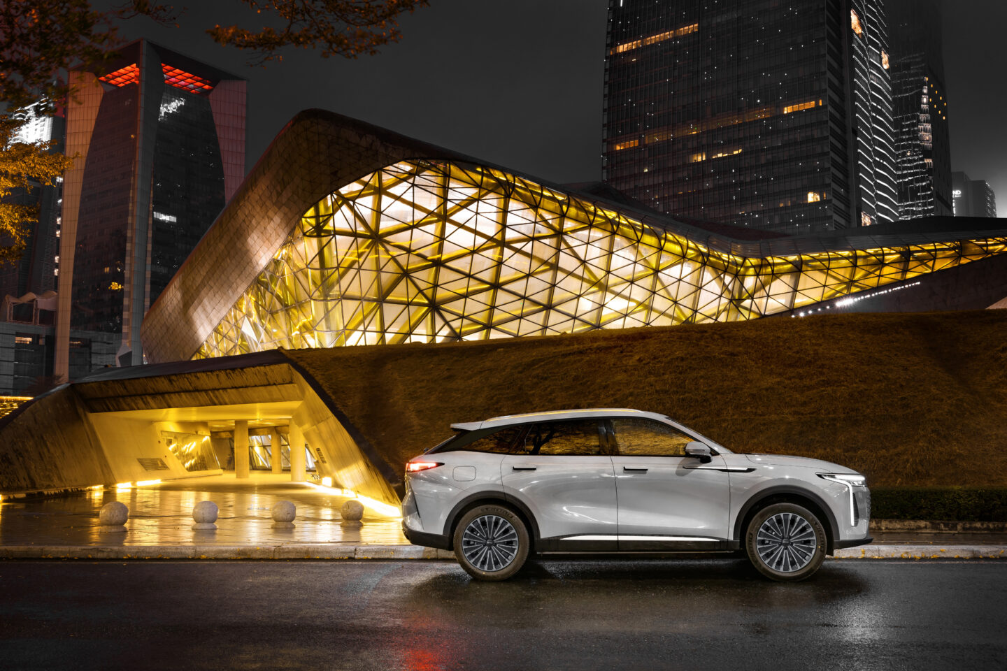 Vista laterale della Omoda 9 Super Hybrid, con linee fluide e design moderno, in un contesto di architettura contemporanea