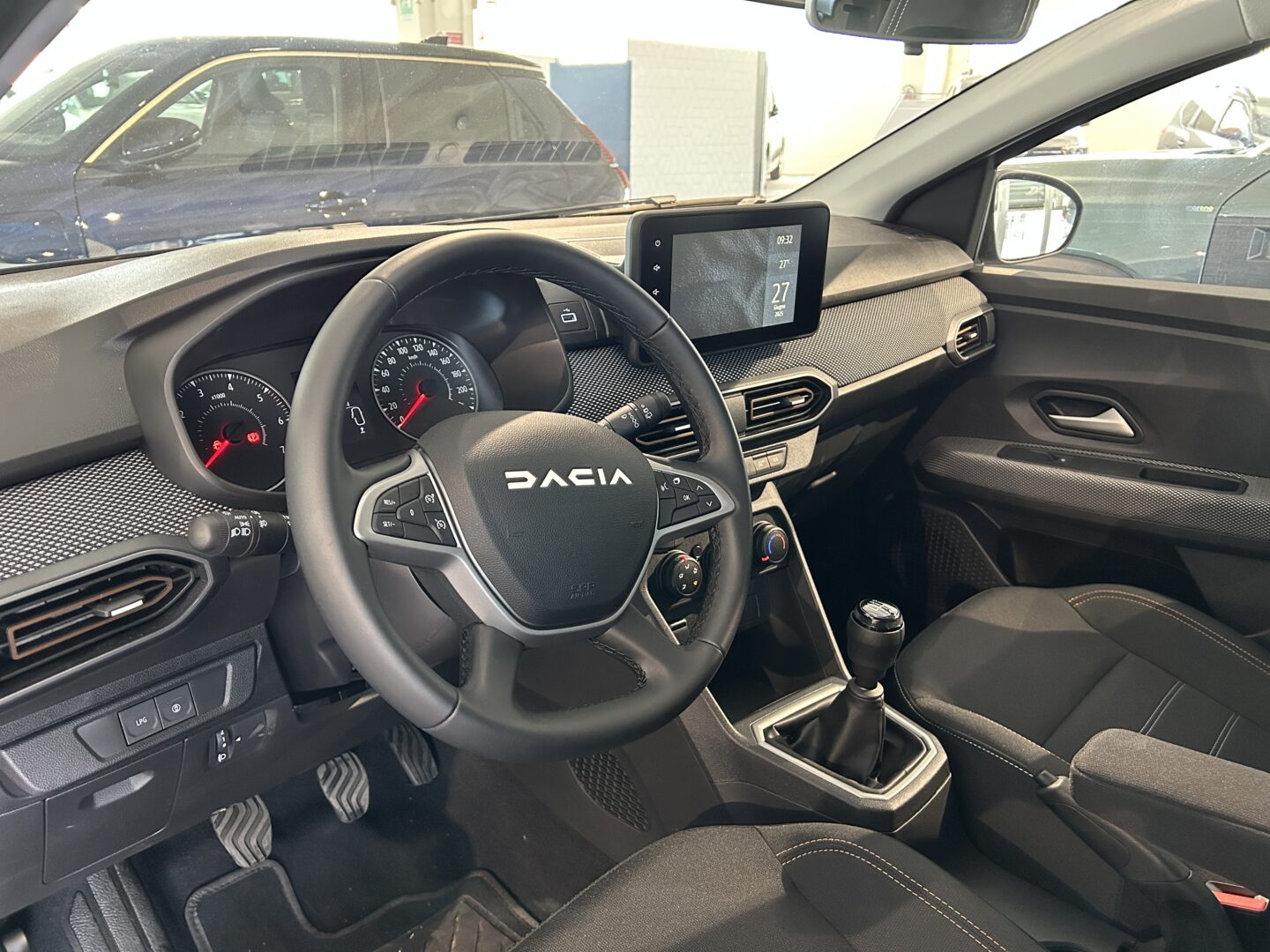 Interni della Dacia Sandero Stepway con volante multifunzione, cruscotto analogico, cambio manuale e display touch centrale, in un abitacolo moderno e funzionale.