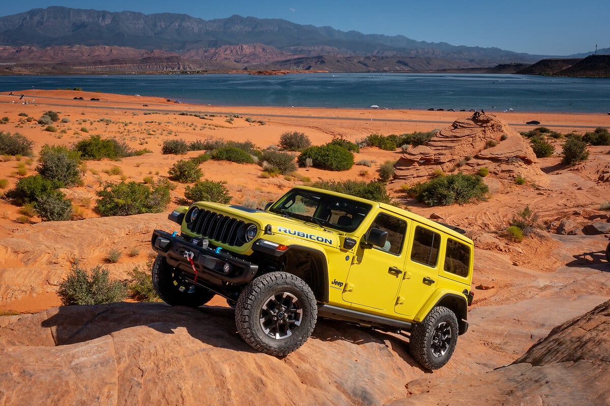 Jeep Wrangler Rubicon gialla su un sentiero roccioso in un paesaggio desertico e un grande lago sullo sfondo